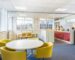 How to Foster a Healthier Work Environment - Yellow tub chairs around a meeting table in front of a red kitchen / meeting room