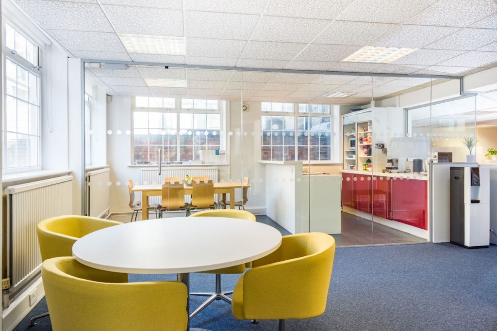 How to Foster a Healthier Work Environment - Yellow tub chairs around a meeting table in front of a red kitchen / meeting room